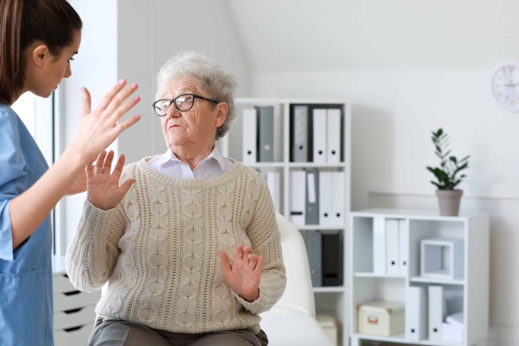 nursing home worker raising hand at elderly person